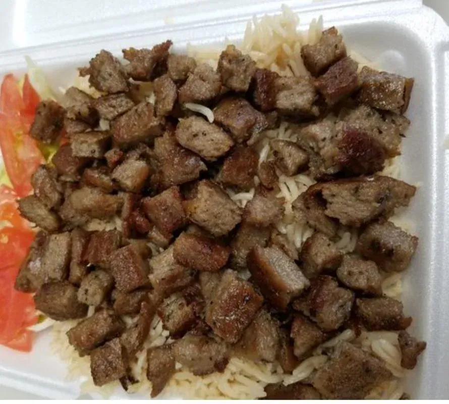 Chopped meat over rice, with tomato and lettuce in a styrofoam container.