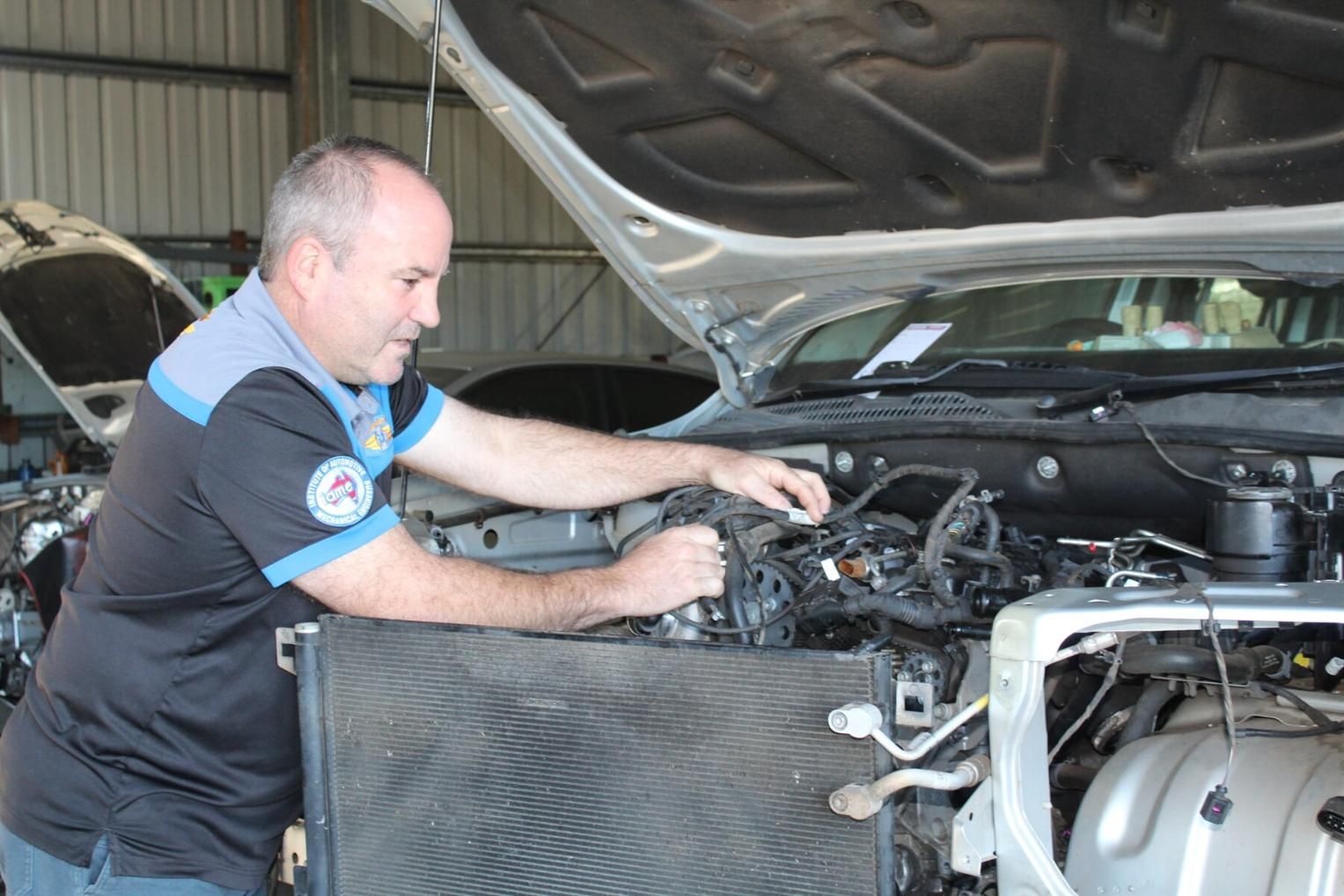 A Man Is Working On The Engine Of A Car With The Hood Open — Mareeba Motors In Mareeba, QLD