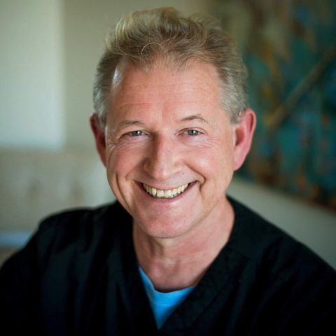 A man in a black shirt and blue shirt is smiling for the camera.