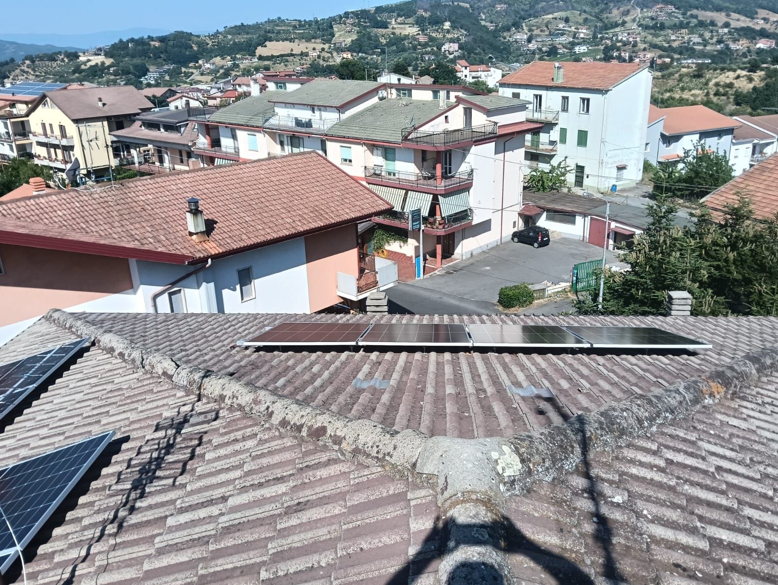 Un tetto con pannelli solari e una città sullo sfondo.