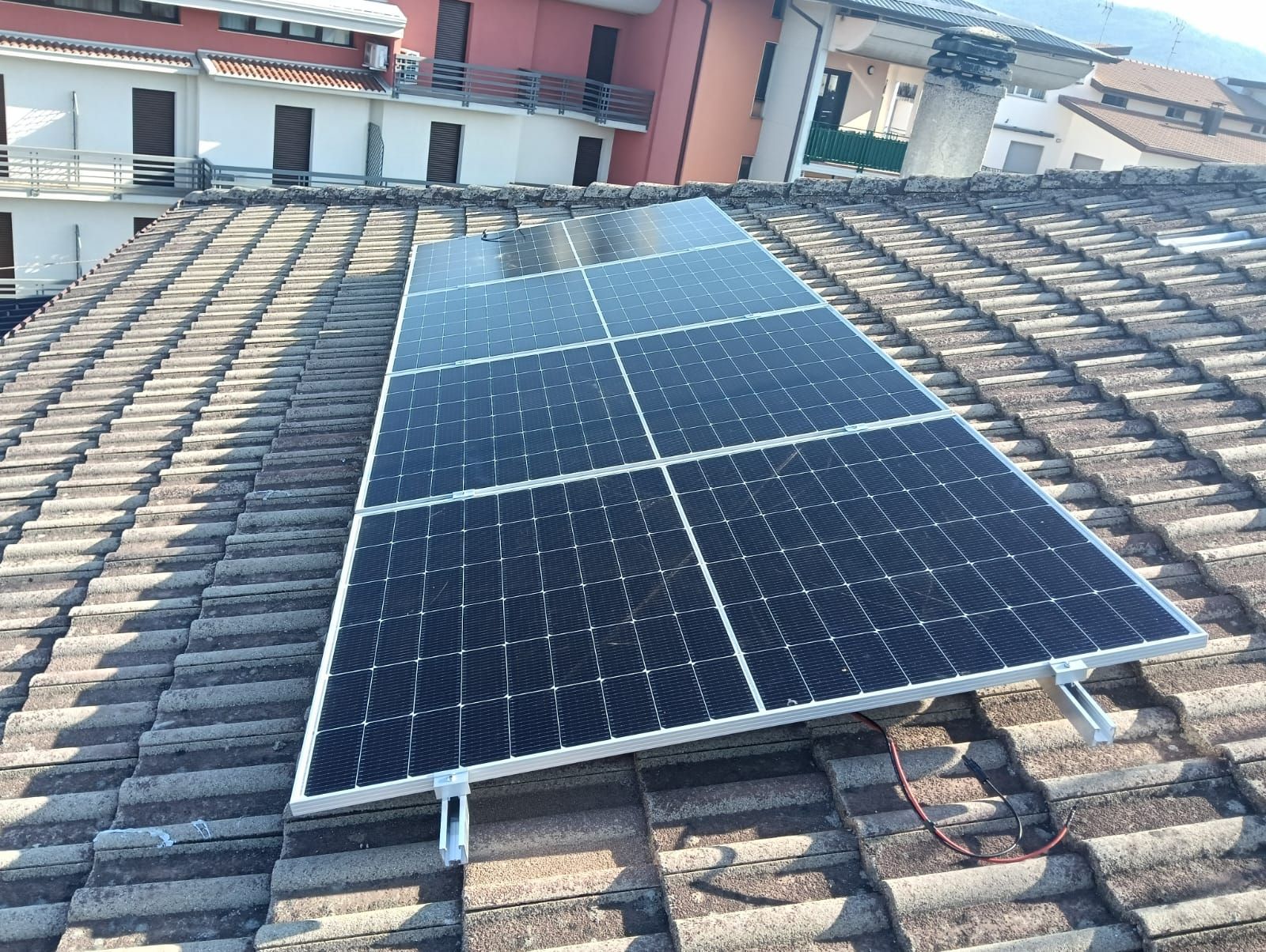 Una fila di pannelli solari è posizionata sopra un tetto di tegole.