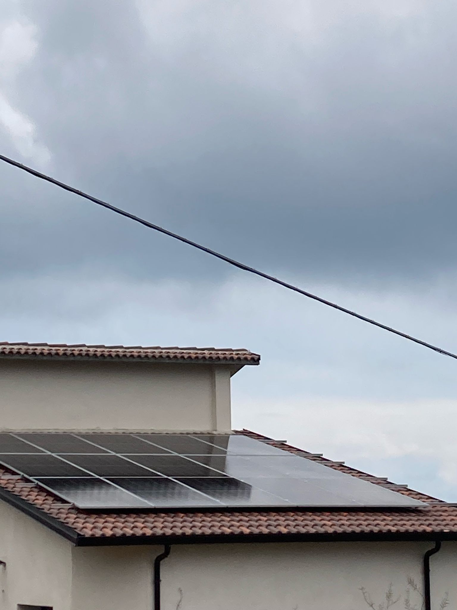 Una casa con pannelli solari sul tetto e un cielo nuvoloso sullo sfondo.