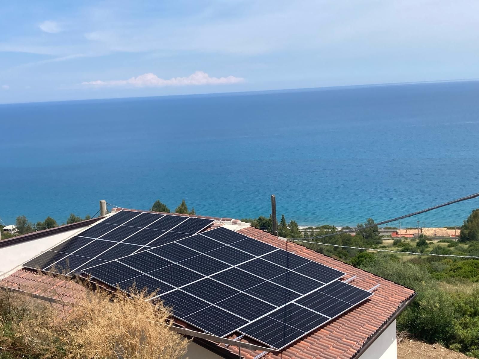 Una casa con pannelli solari sul tetto con vista sull'oceano.