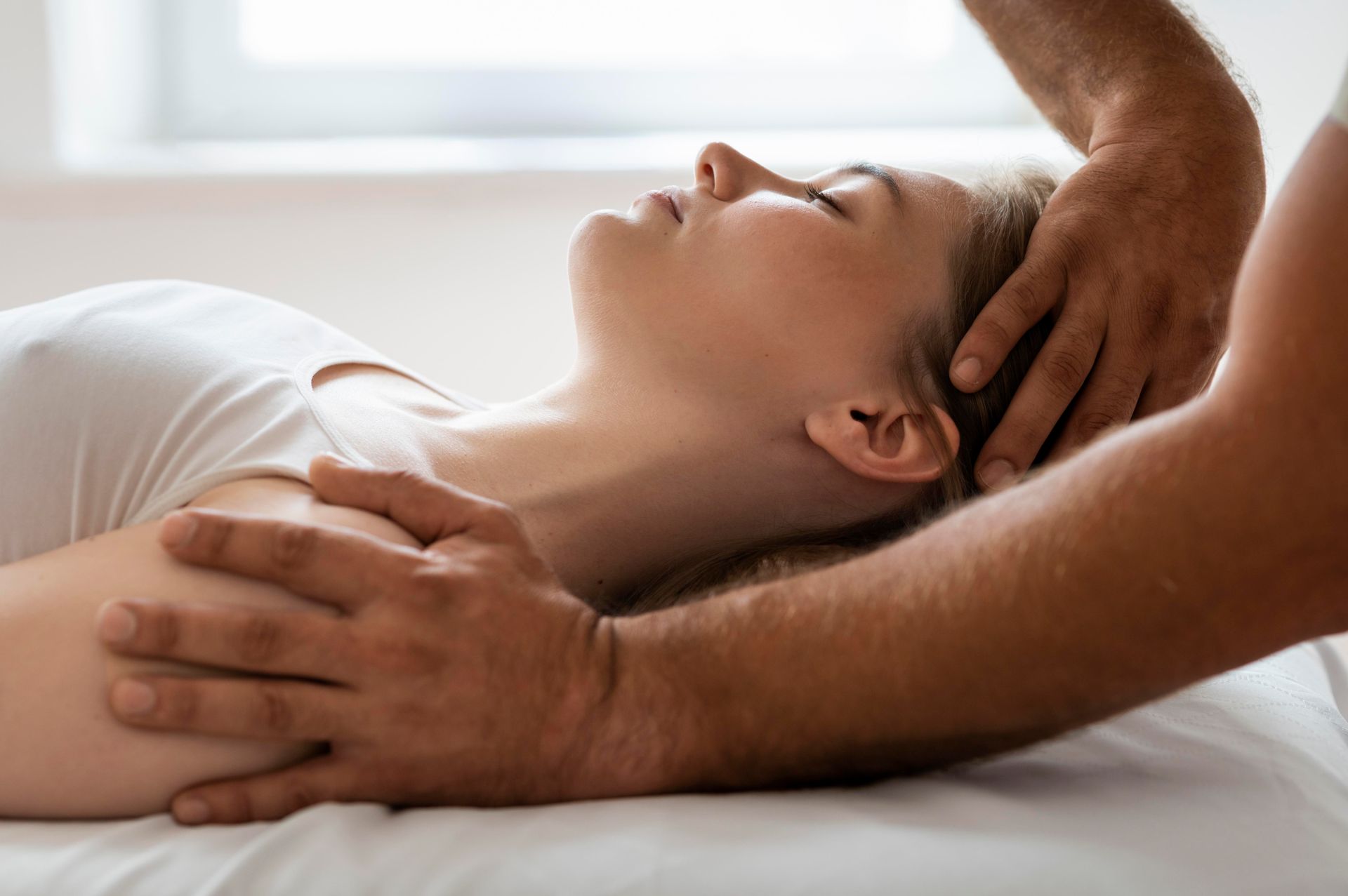 A woman is laying on a bed getting a massage from a man.