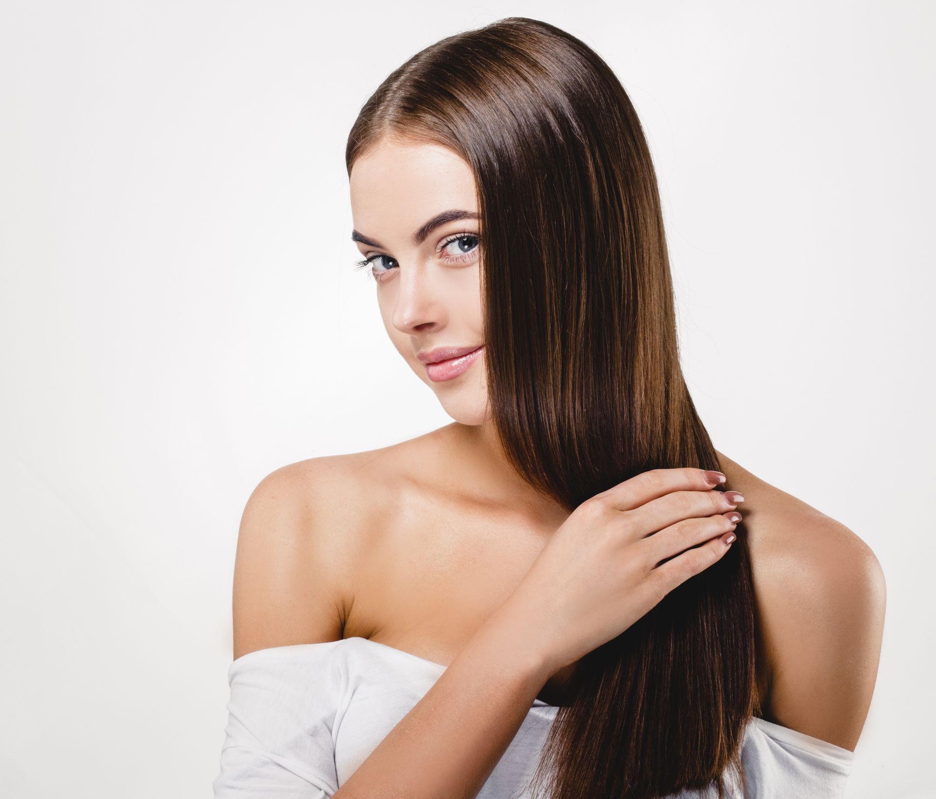 A woman with long hair is holding her hair in her hand.