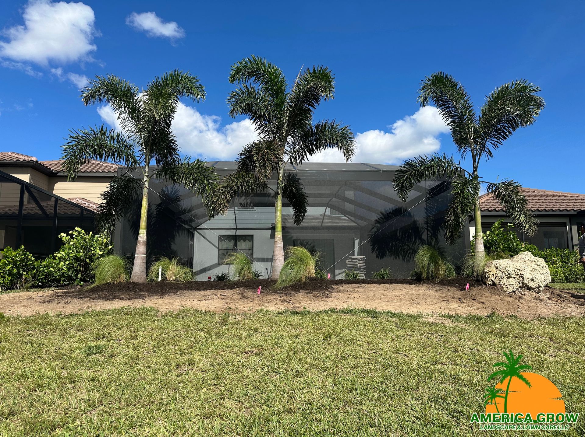 Palm trees stand in front of a house, bordered by a wooden fence, creating a tropical and inviting atmosphere.