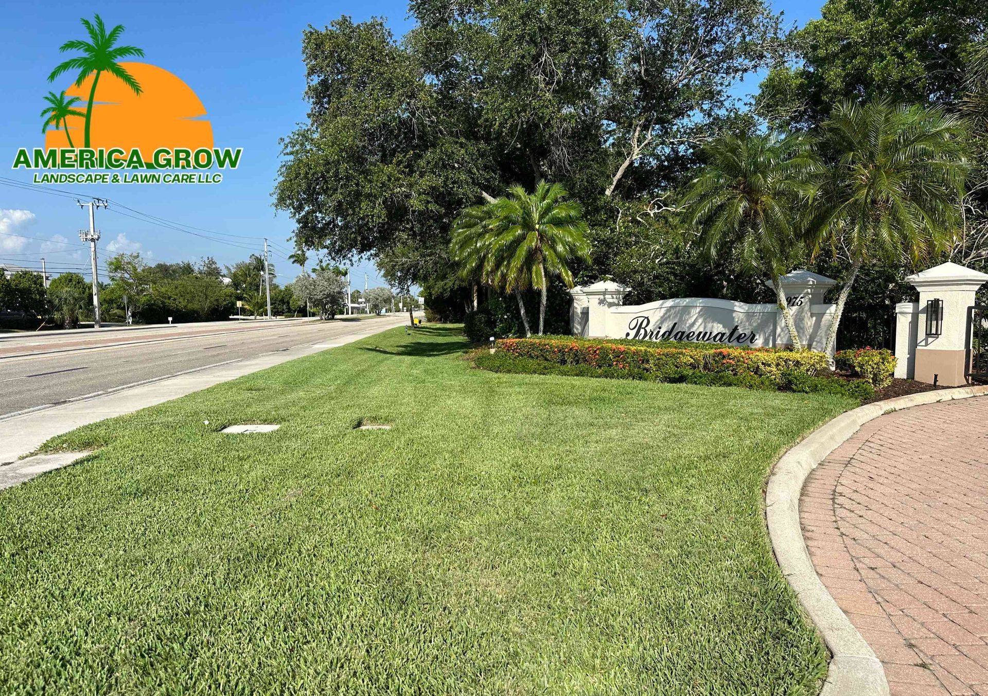 Lush green lawn with a palm tree logo and entrance sign under a blue sky.