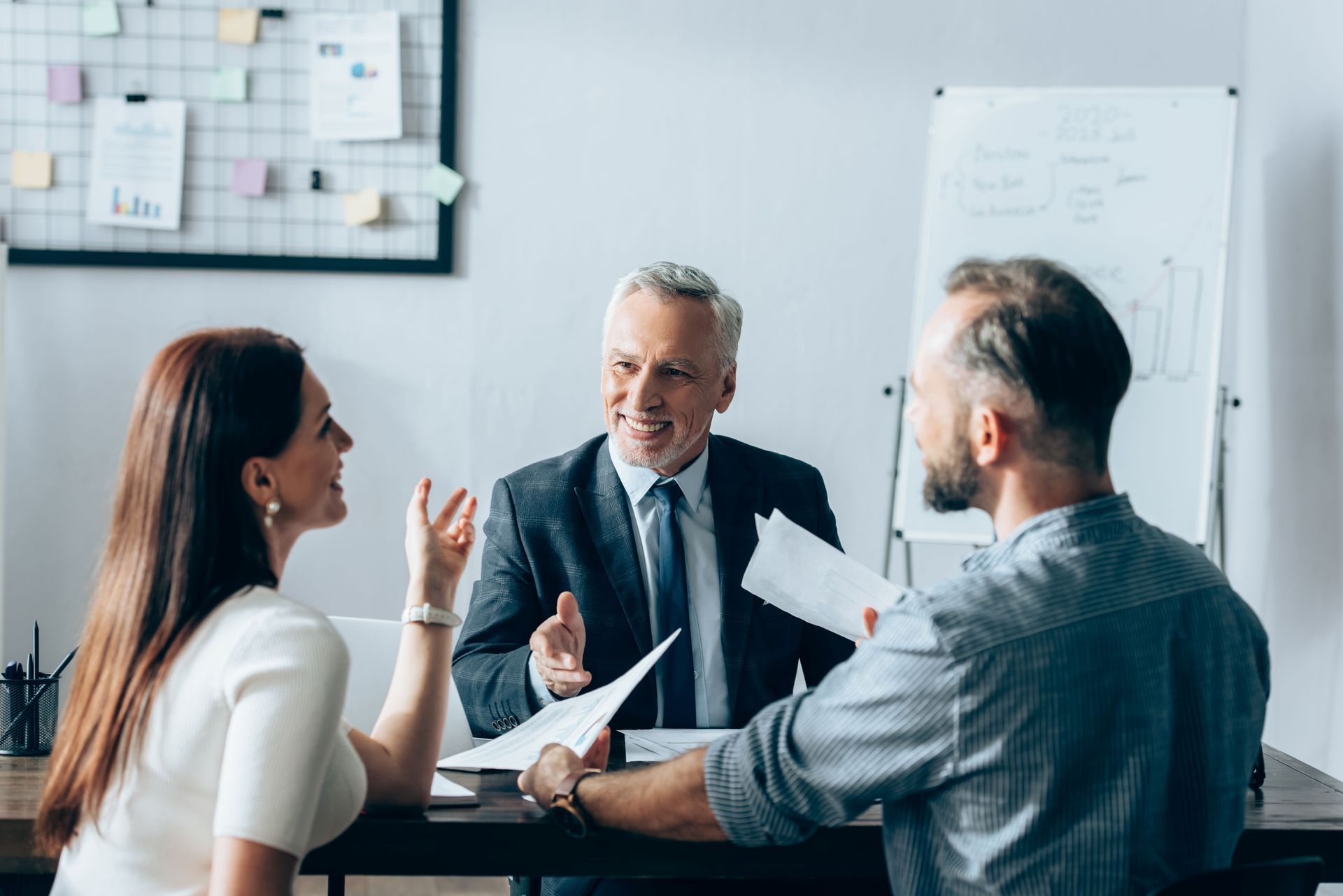 Couple in consultation with a financial advisor at a desk. Documents present.