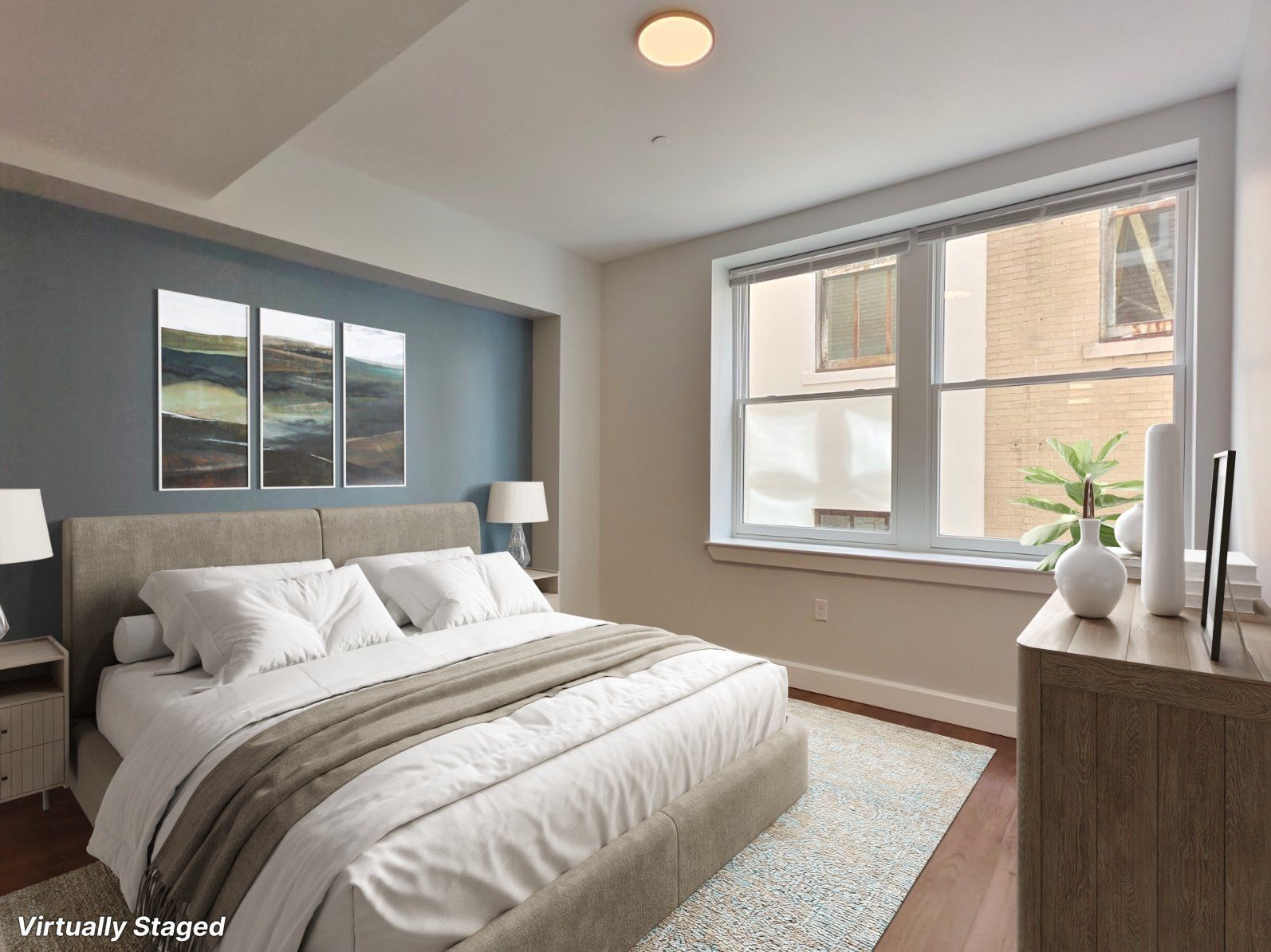 Bedroom with blue accent wall, double bed, large window, and wooden dresser.
