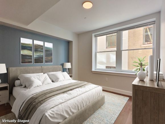 Bedroom with blue accent wall, double bed, large window, and wooden dresser.
