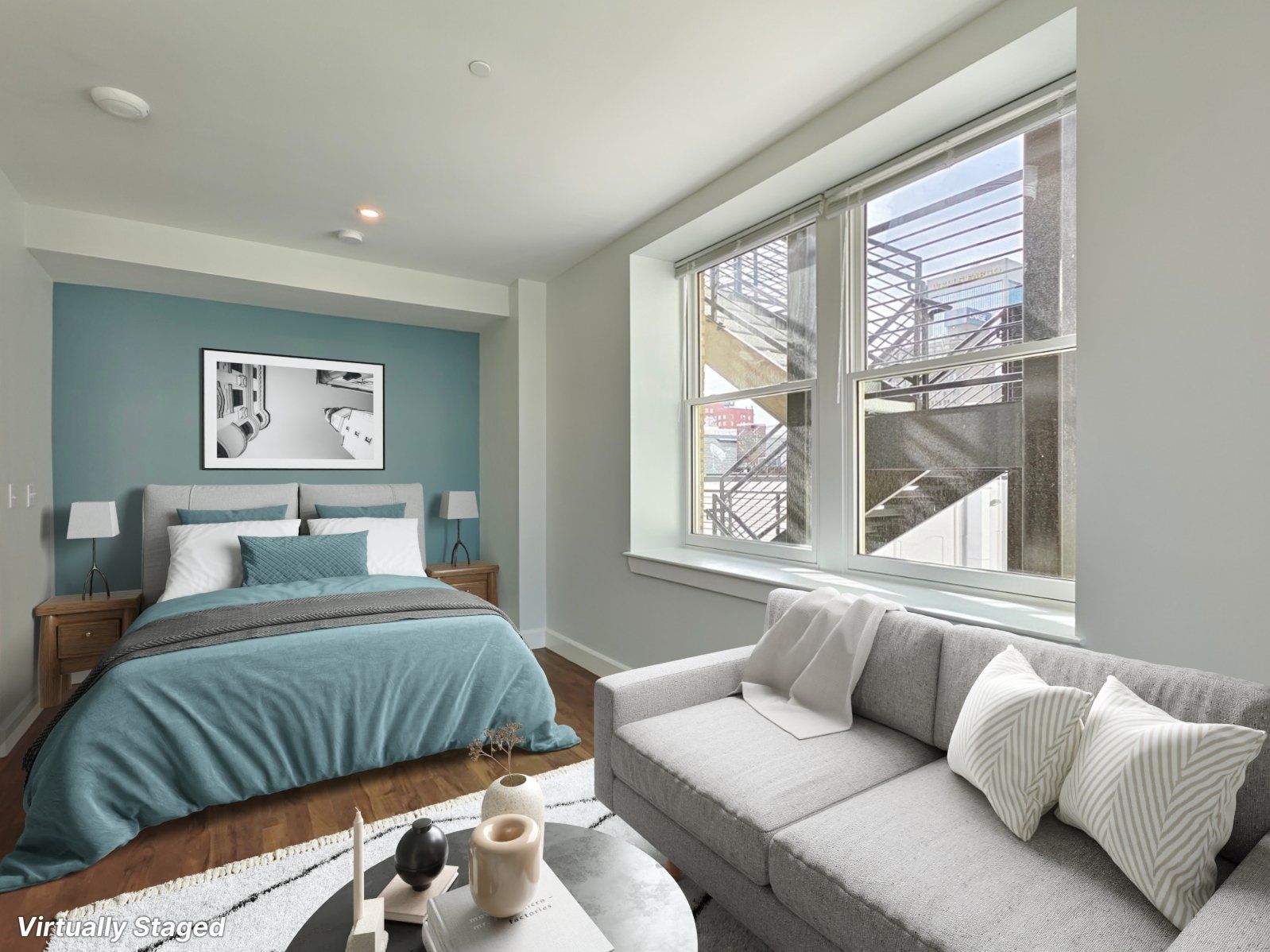 Bedroom with bed, sofa, and large window. Teal accent wall, neutral tones, wooden floor.
