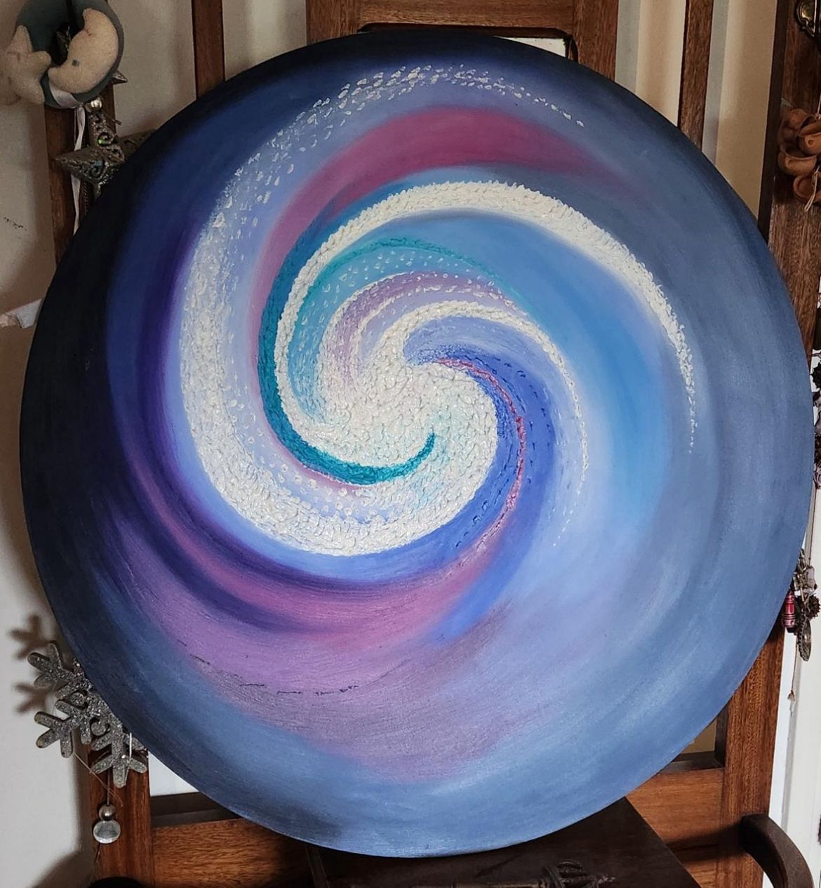 Pintura abstracta en espiral azul y violeta sobre lienzo circular.