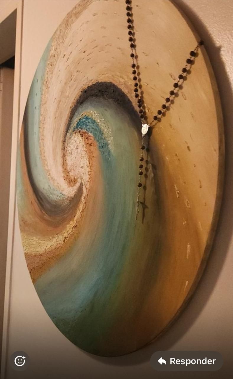 Cuadro abstracto ovalado con un rosario sobre él, con remolinos de colores azul, tostado y marrón.