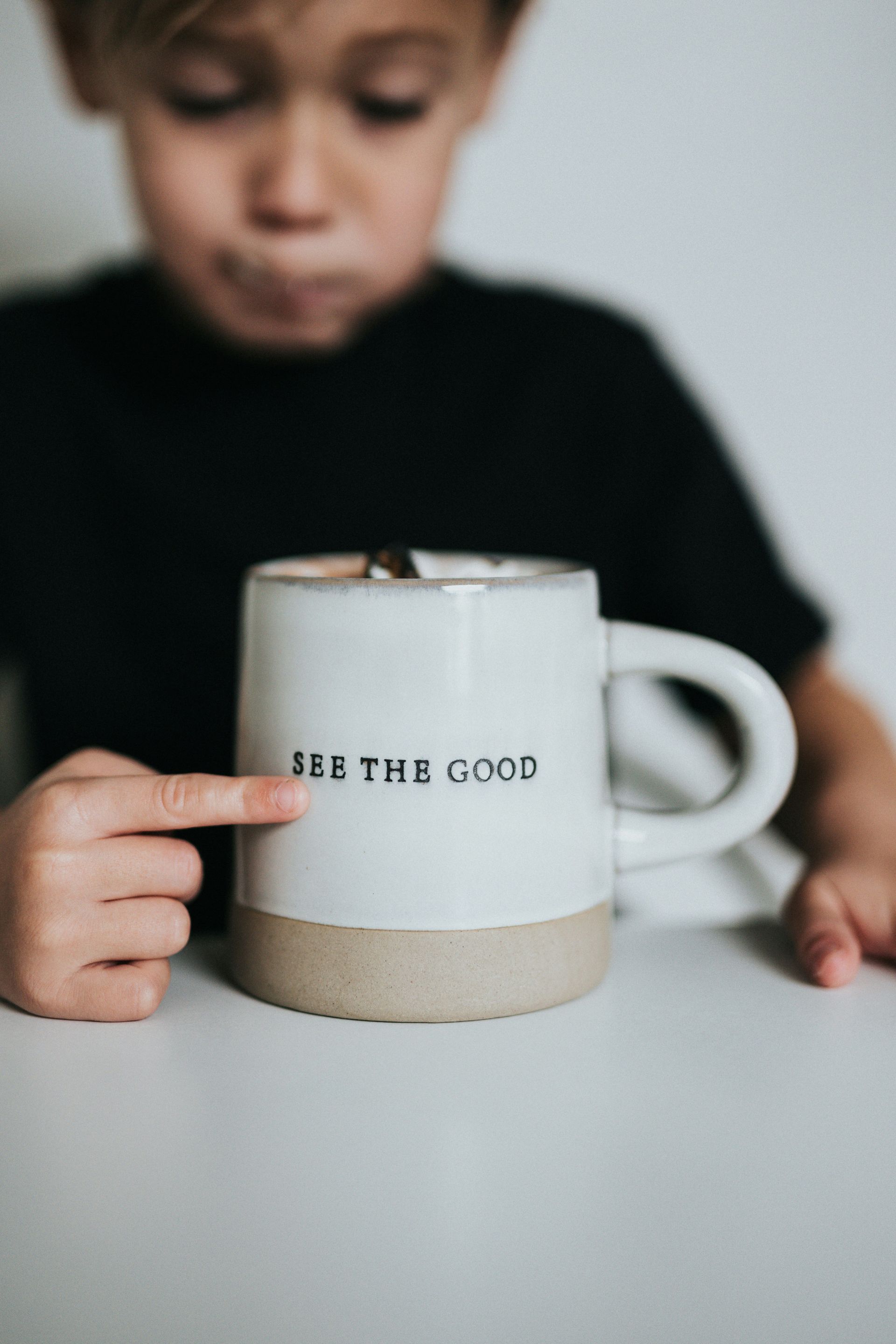 Boy pointing at a mug which has the words 
