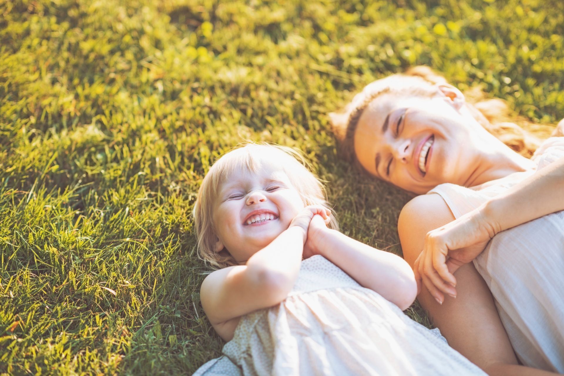 Mother and daughter lying on the grass, laughing