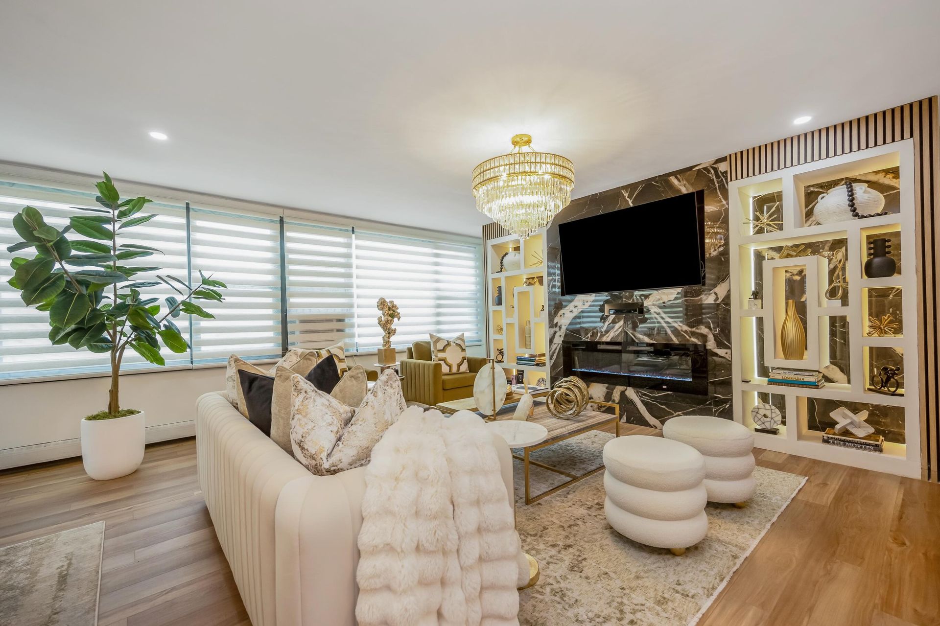 Bright modern living room with cream sofa, gold accents, large TV, and mirrored wall paneling