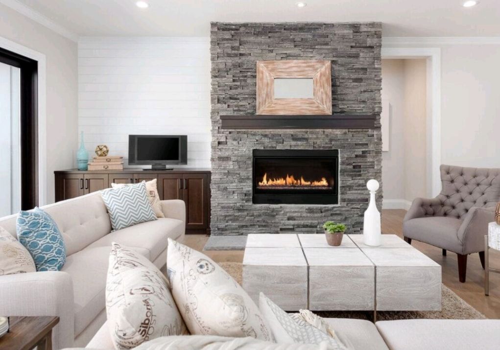 Modern living room with stone fireplace, beige sofa, tufted chair, and white ottoman coffee table