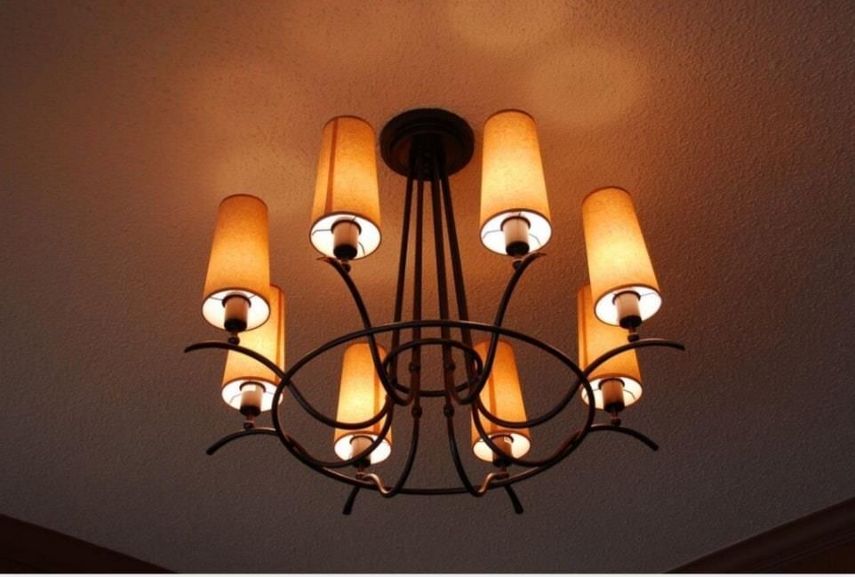 Black wrought-iron chandelier with warm amber lamps on a ceiling