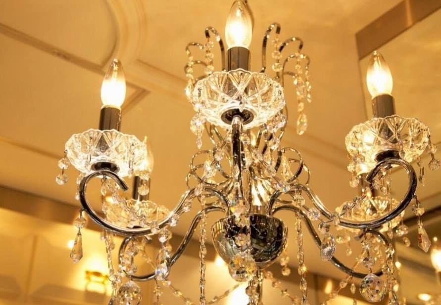 Crystal chandelier with lit bulbs hanging from a ceiling