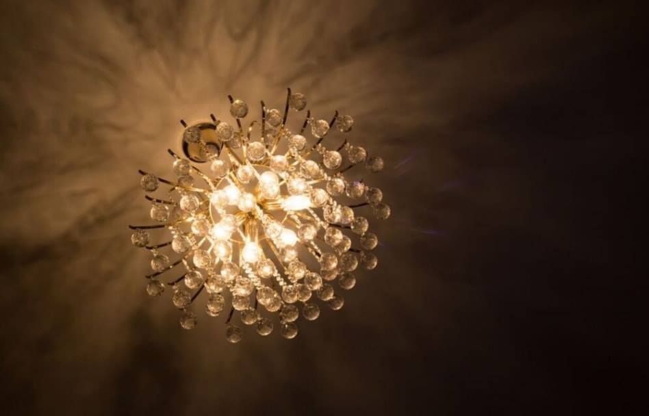 Warm chandelier with glass drops glowing against a dark ceiling