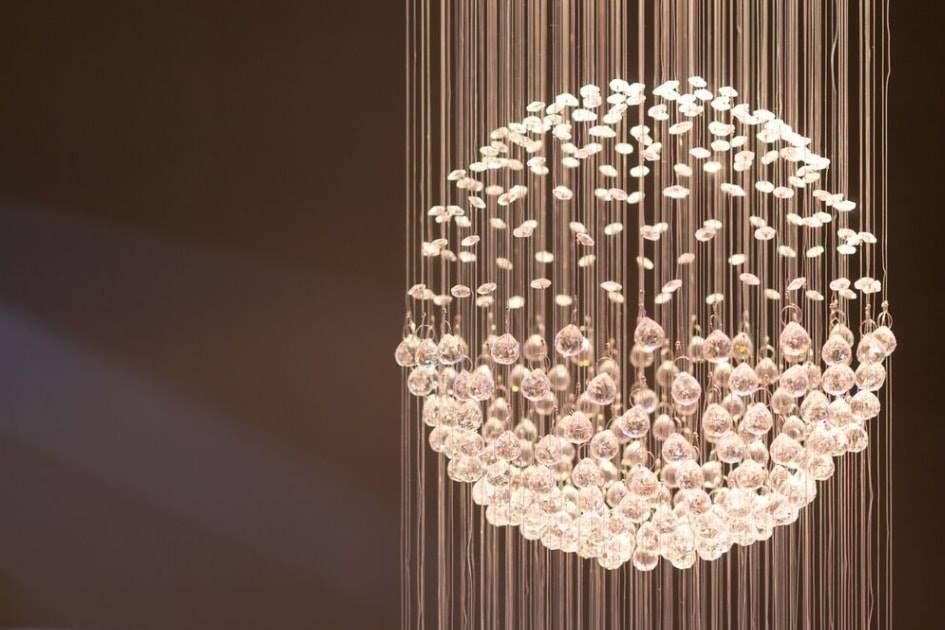 Decorative spherical chandelier of dangling crystal-like beads against a dark wall