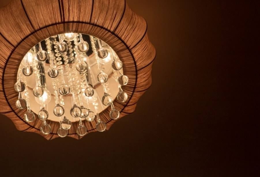 Beige chandelier with dangling crystals against a dark ceiling