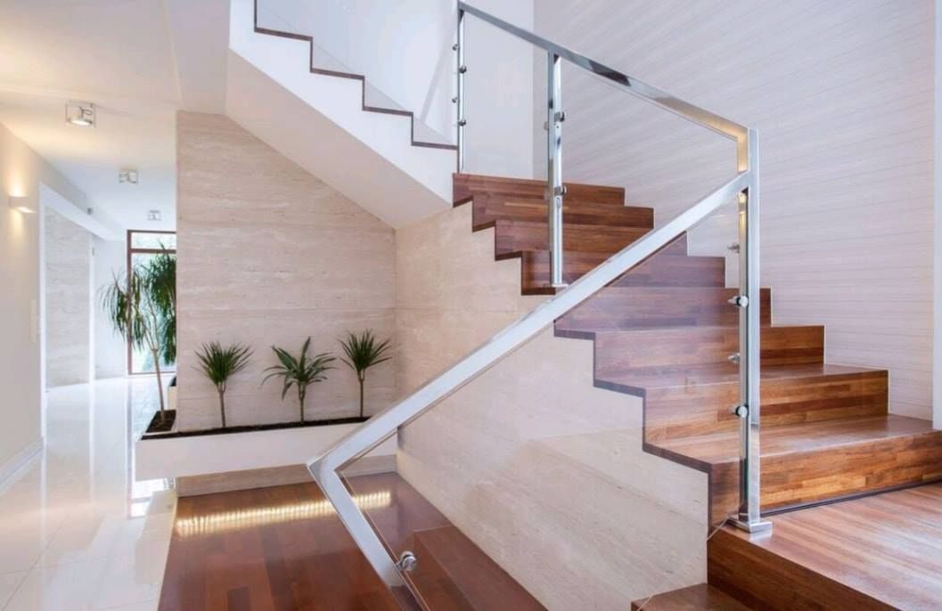 Modern indoor staircase with wood steps, glass railing, and white walls in a bright entryway