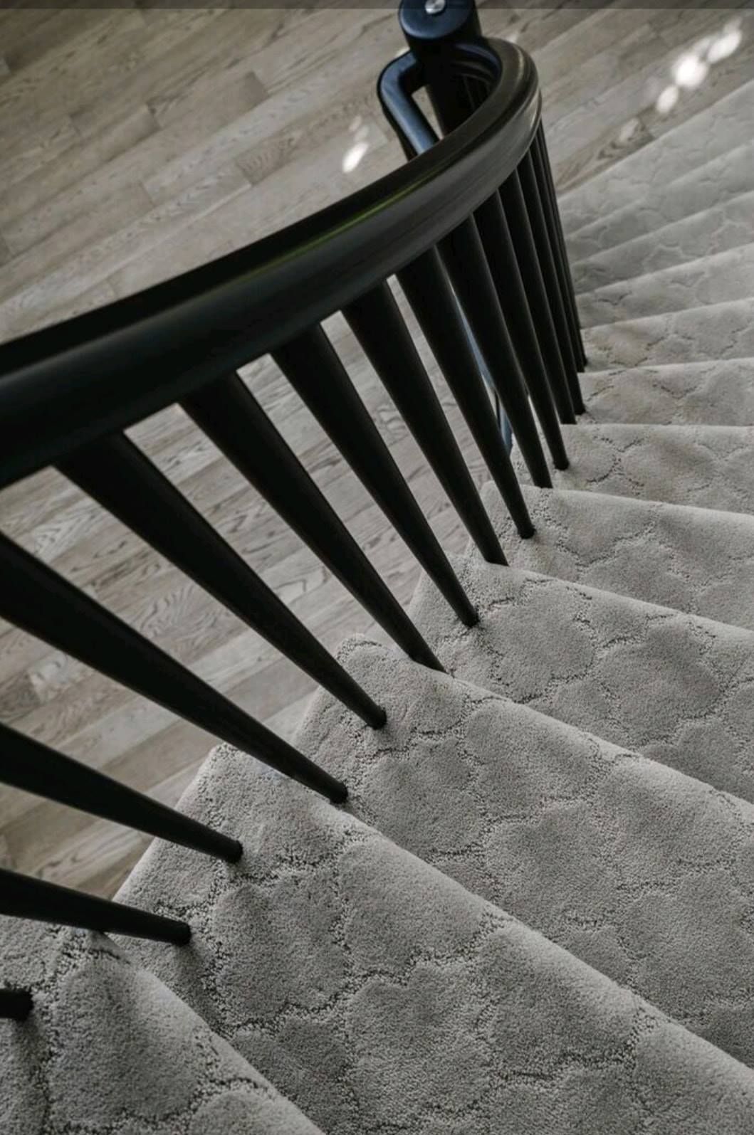 Curved carpeted staircase with black railing viewed from above