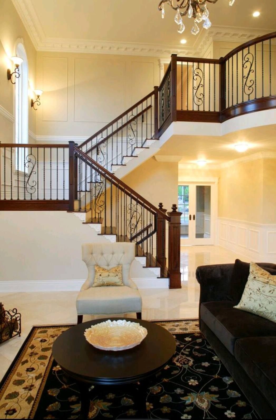 Elegant foyer with curved staircase, chandelier, and dark wood railings