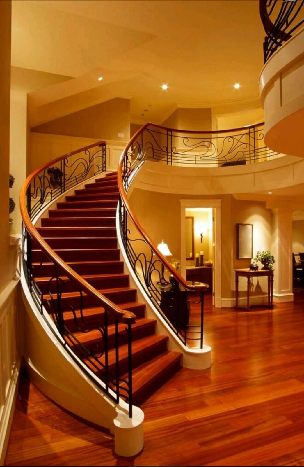 Elegant curved staircase with red carpet in a warm-lit modern foyer