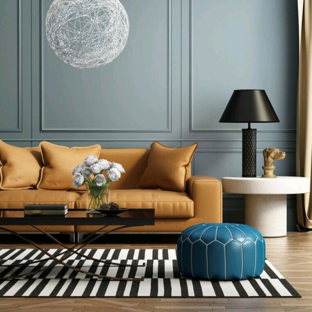 Modern living room with tan sofa, blue ottoman, striped rug, and black lamp against blue paneled wall
