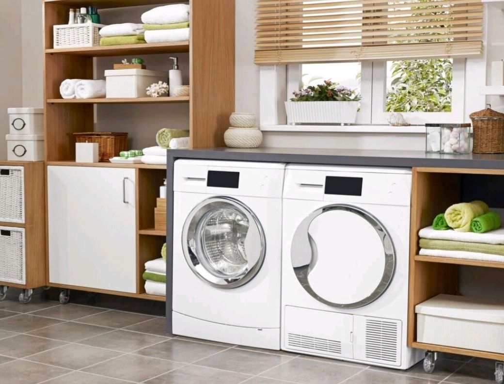 Modern laundry room with white washer and dryer, wooden shelves, and woven baskets.