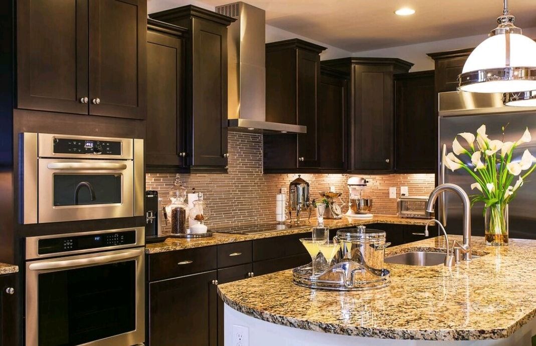 Modern kitchen with dark cabinets, granite island, built-in oven, and hanging pendant light