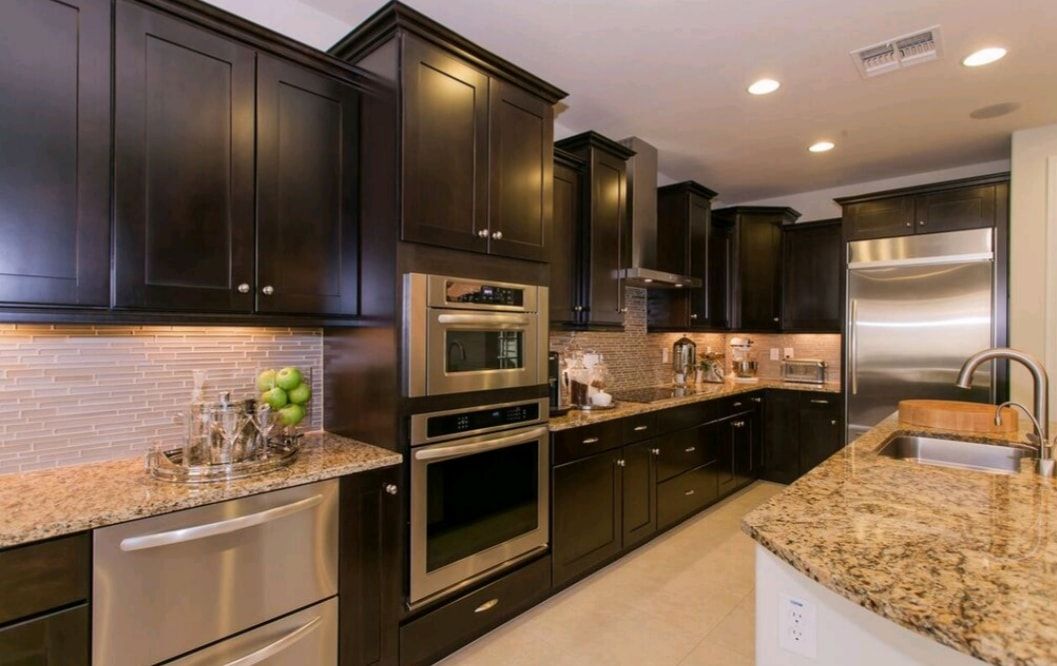Modern kitchen with dark cabinets, stainless steel appliances, and granite countertops
