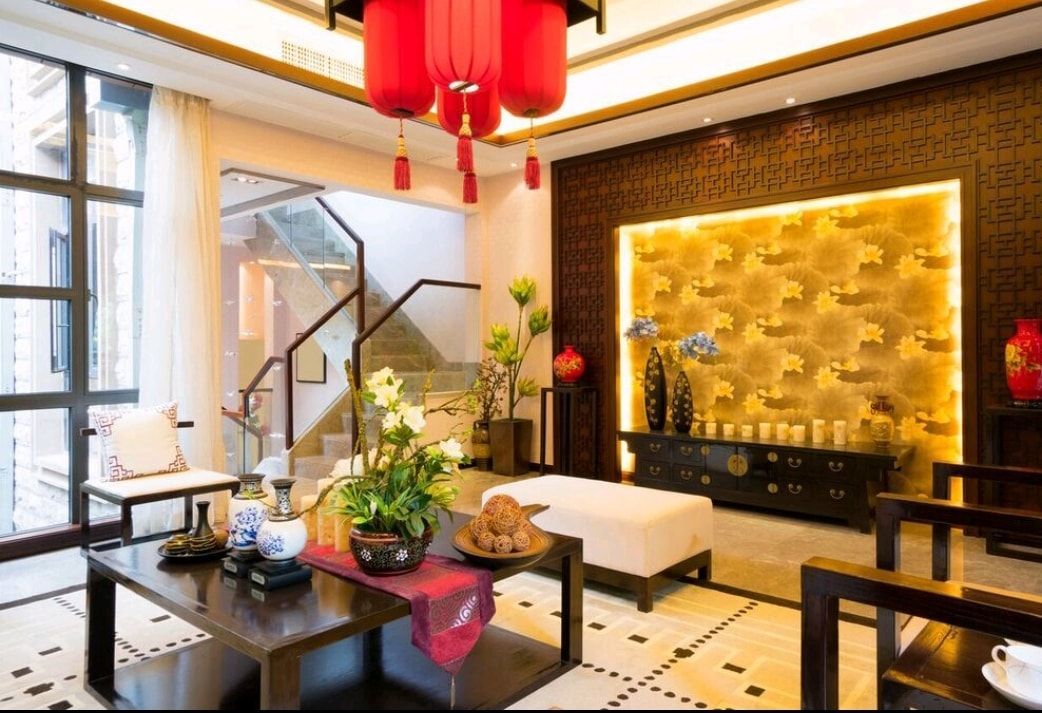 Bright modern living room with red lanterns, gold accent wall, black furniture, and large windows