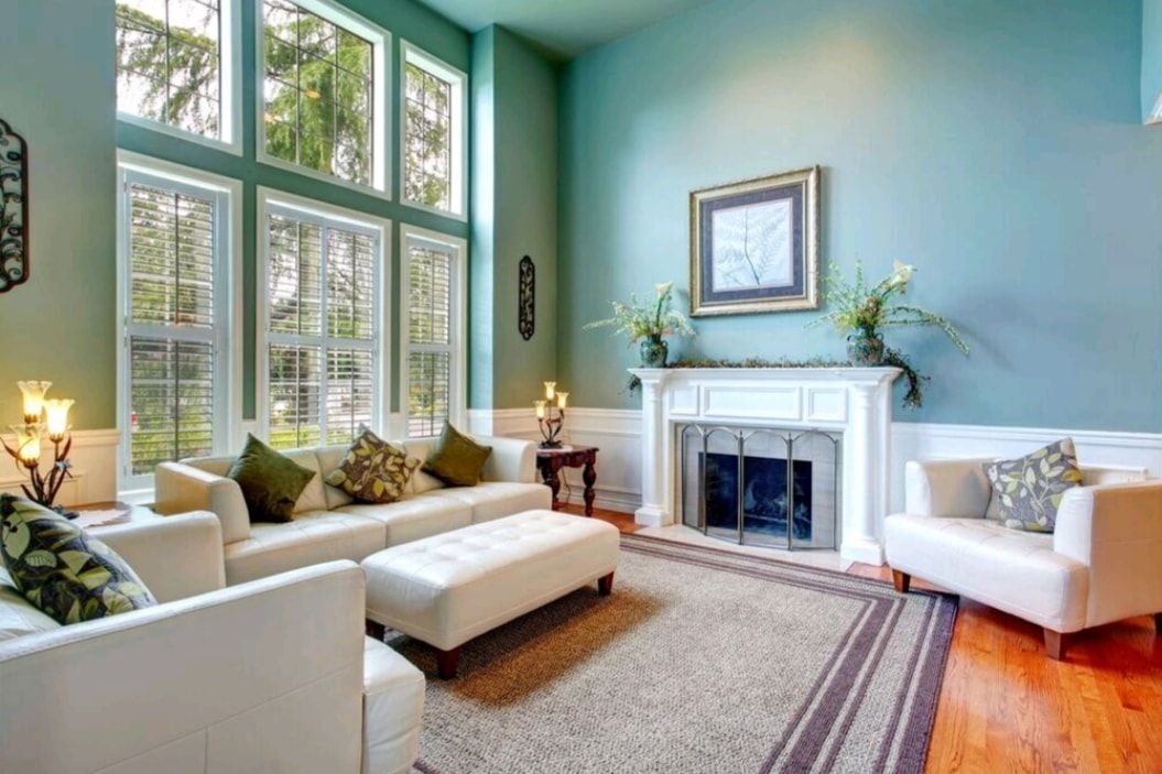 Bright living room with large windows, white sofas, a fireplace, and teal walls