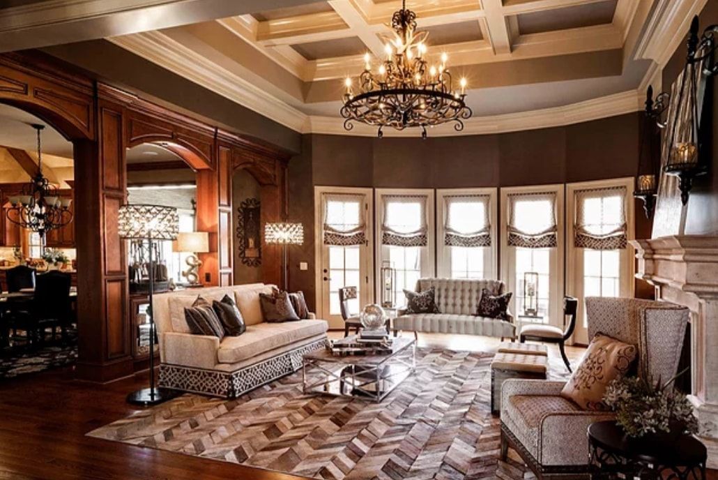 Elegant living room with ornate ceiling, chandelier, tall windows, and classic upholstered furniture
