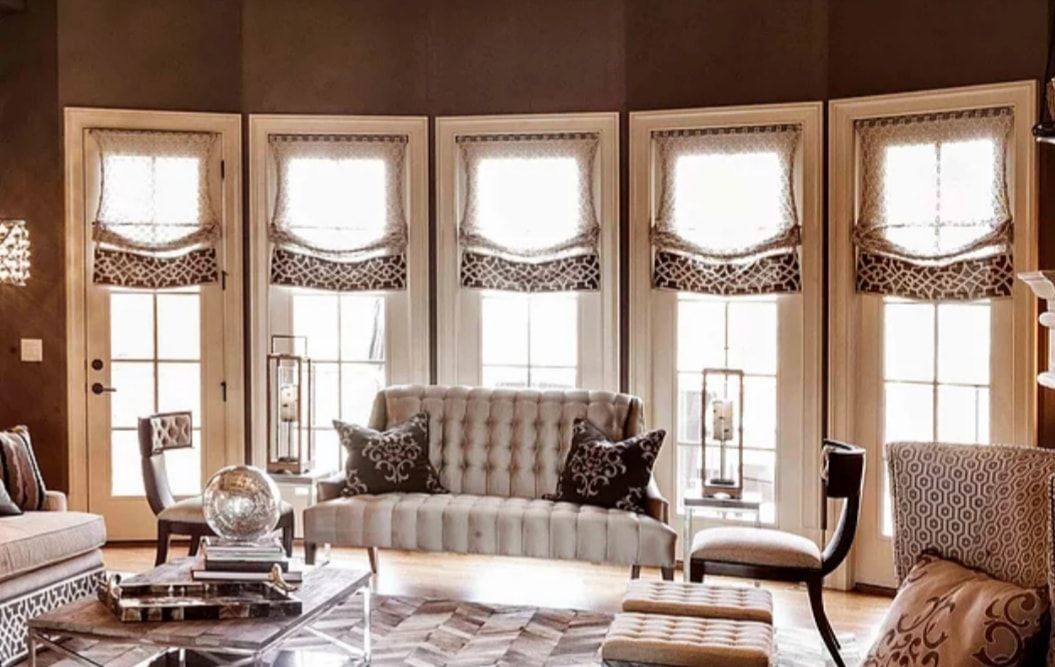 Elegant living room with bay windows, patterned sofas, coffee table, and warm neutral decor