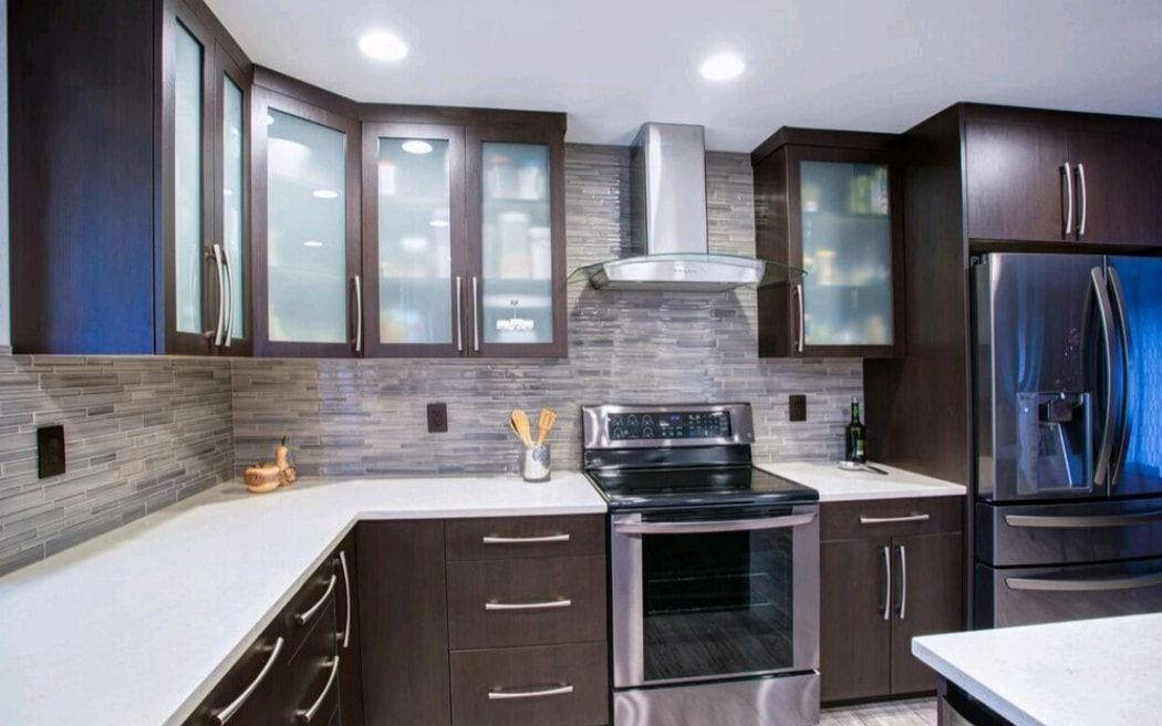 Modern kitchen with dark wood cabinets, stainless steel stove, and gray tile backsplash