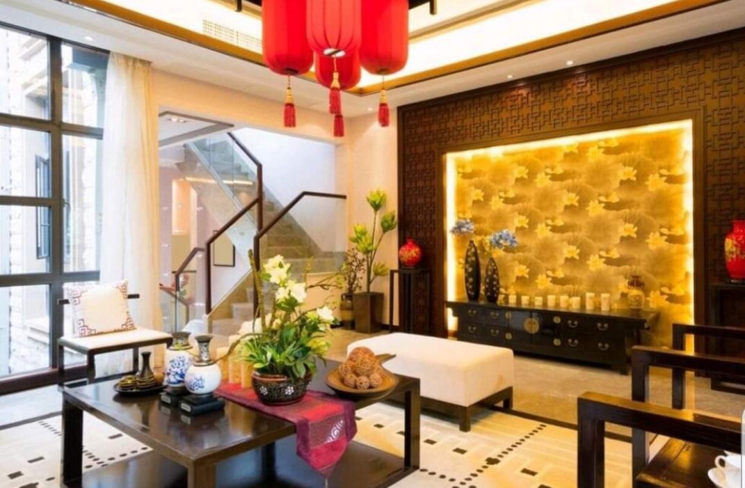 Modern living room with red lanterns, black furniture, and a gold-lit wall panel