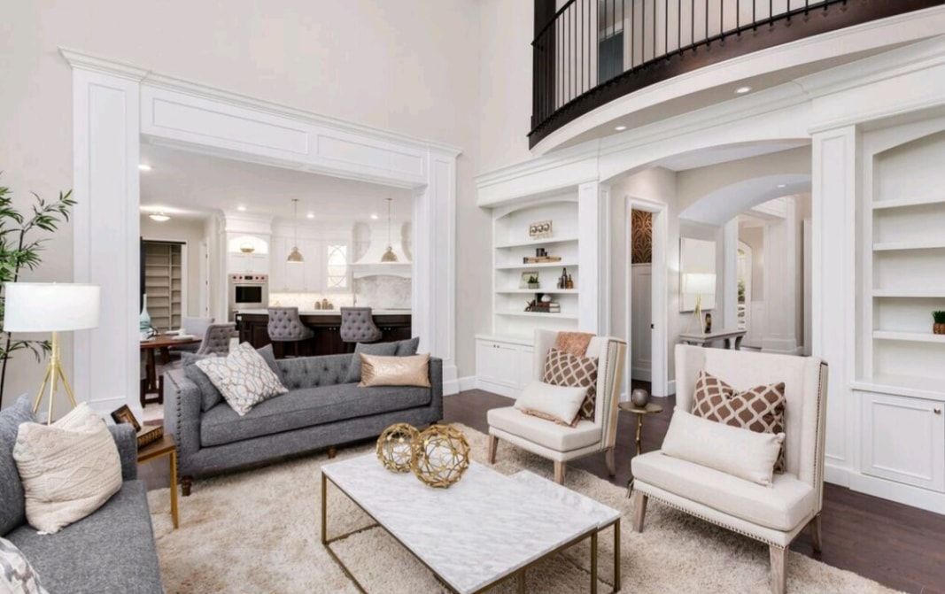 Bright airy living room with white trim, gray sofa, cream chairs, and marble coffee table in an open floor plan