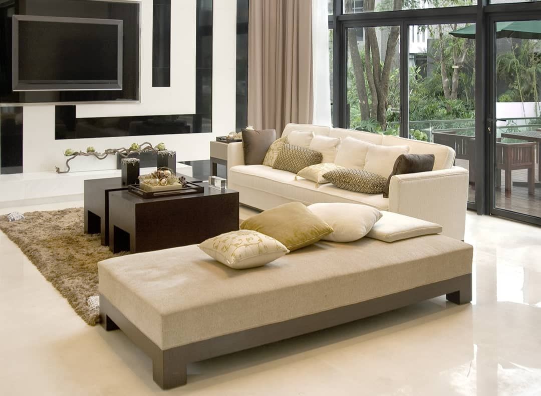 Modern beige living room with sectional sofa, chaise lounge, coffee table, rug, and large windows