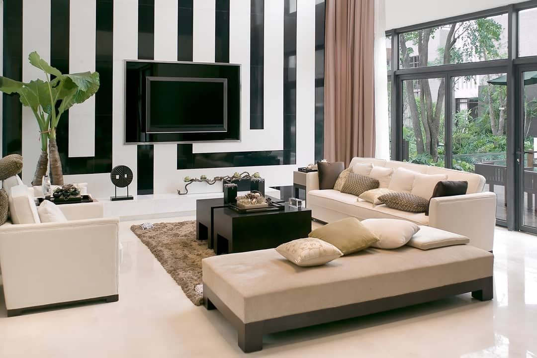 Modern living room with white and beige furniture, black striped wall, and large windows.