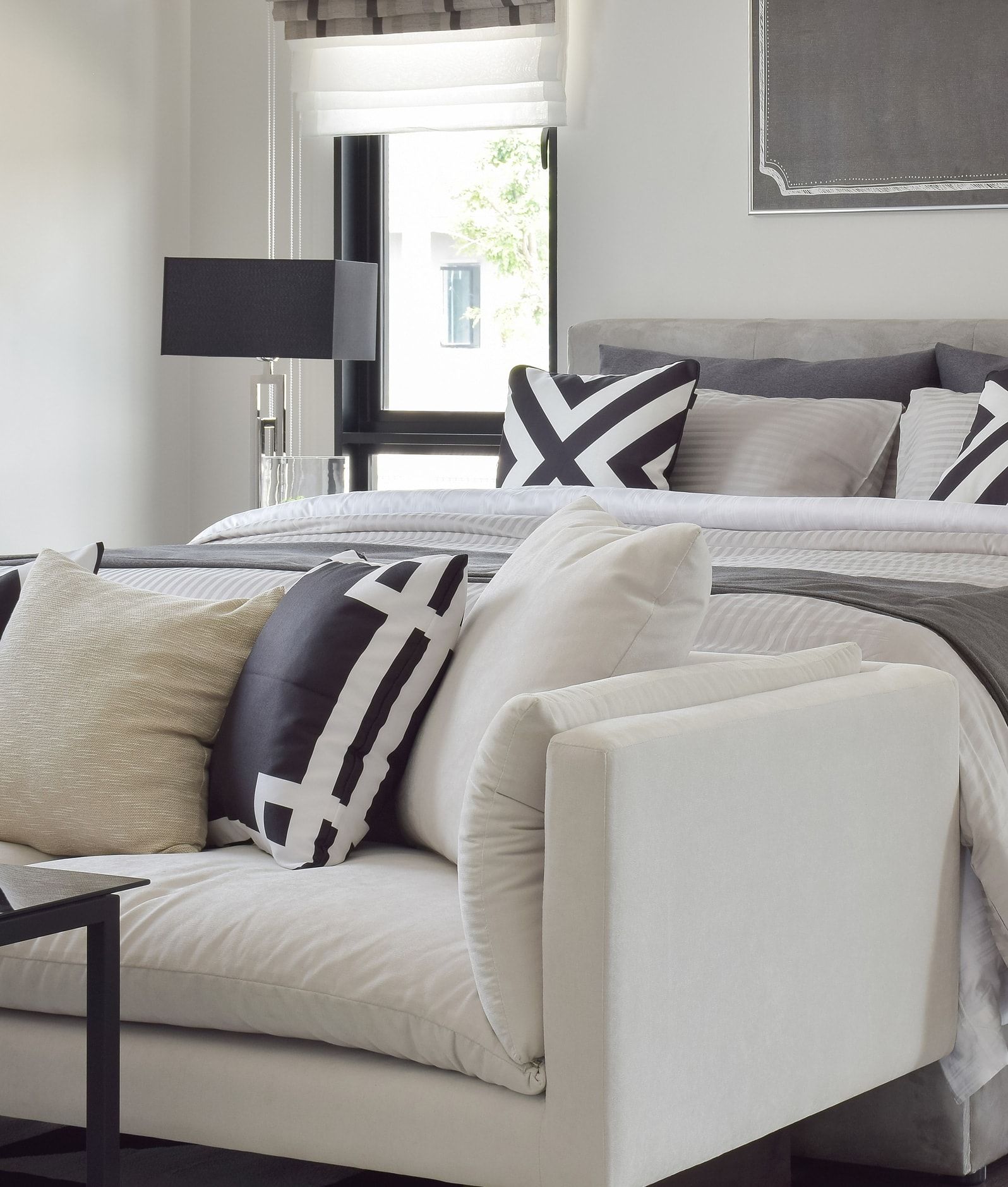 Modern bedroom with a white sofa, gray bed, and black-and-white accent pillows