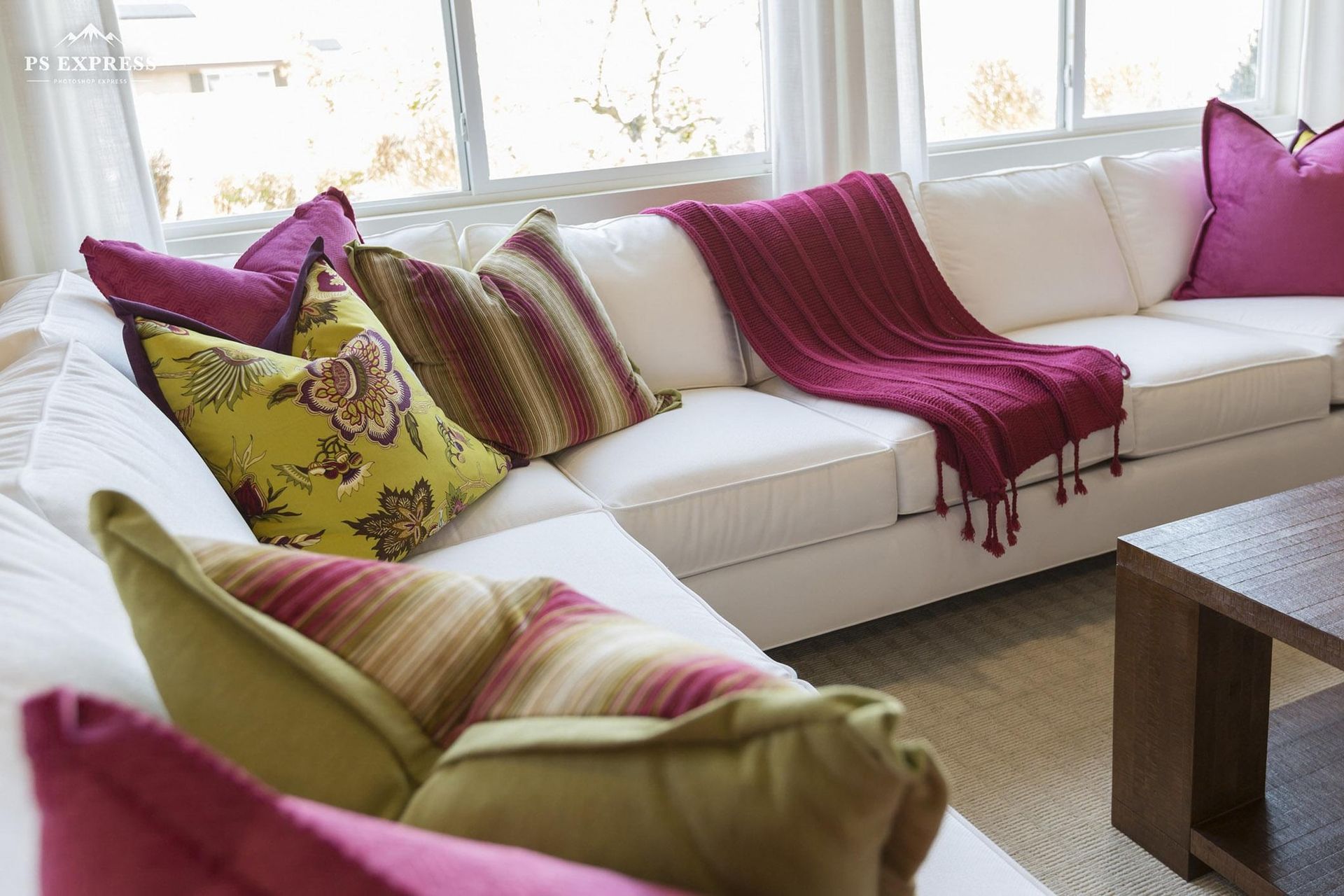White sofa with magenta throw and patterned pillows in a bright living room by the window