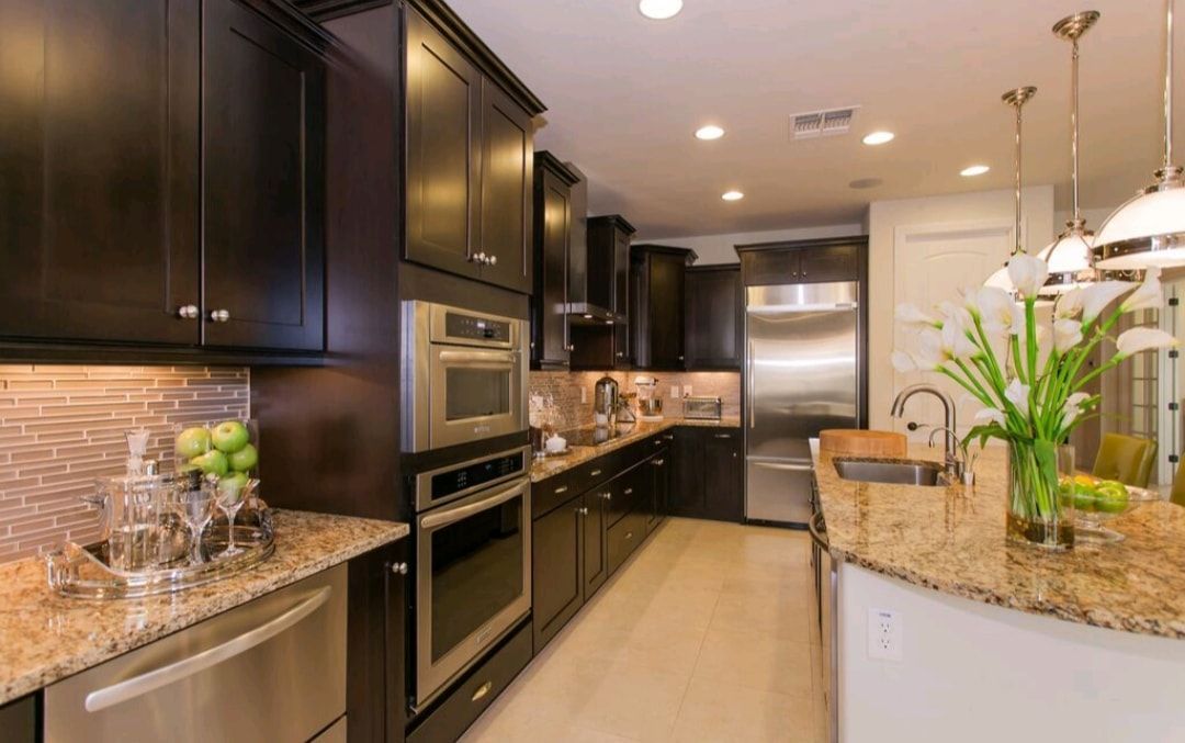 Modern kitchen with dark cabinets, granite countertops, stainless appliances, and a bright island with flowers