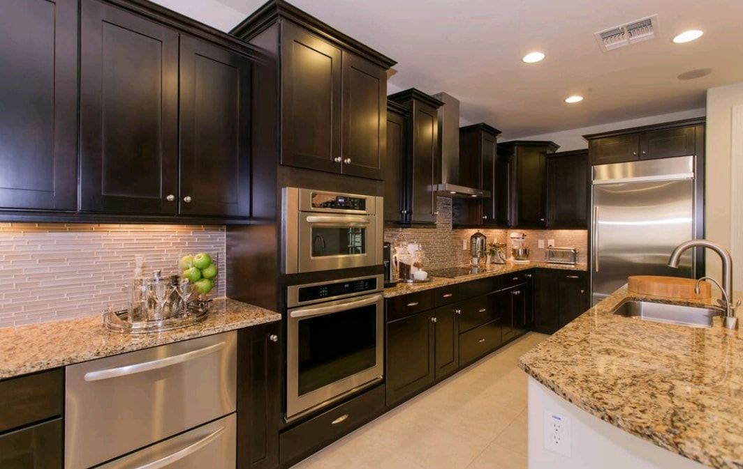 Modern kitchen with dark wood cabinets, stainless steel appliances, and granite countertops.