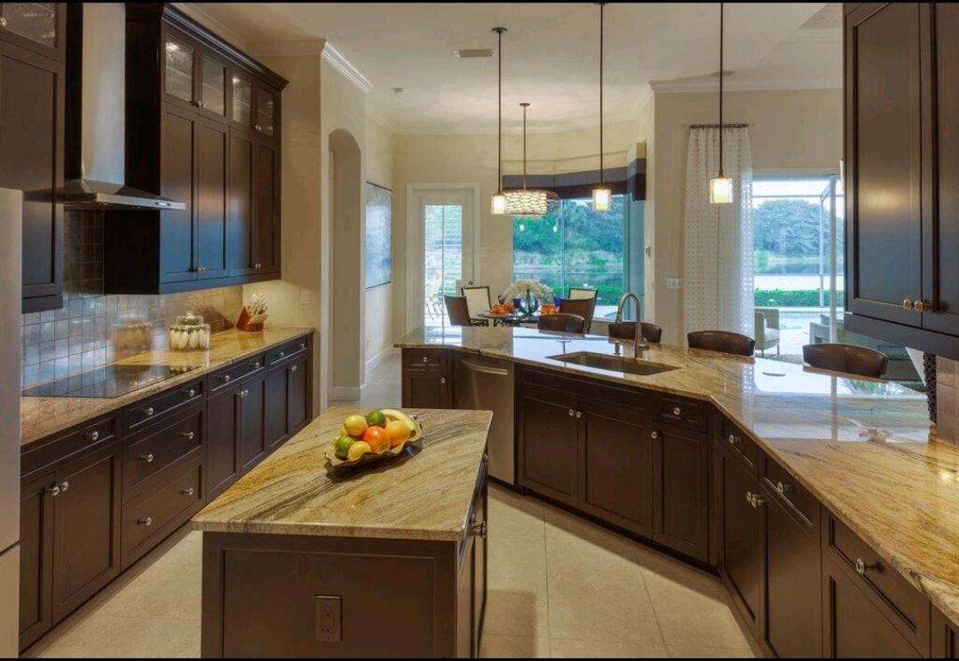 Spacious modern kitchen with dark cabinets, granite island, and large windows overlooking greenery