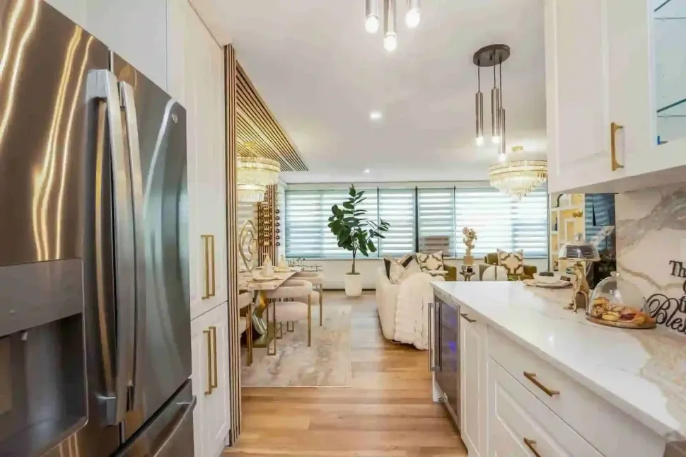 Bright modern kitchen opening to dining nook, with white cabinets, stainless fridge
