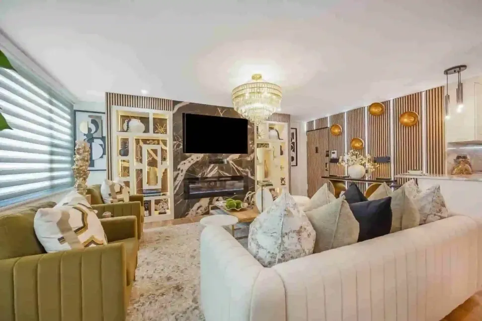 Bright, elegant living room with cream sofas, gold accents, chandelier, and fireplace